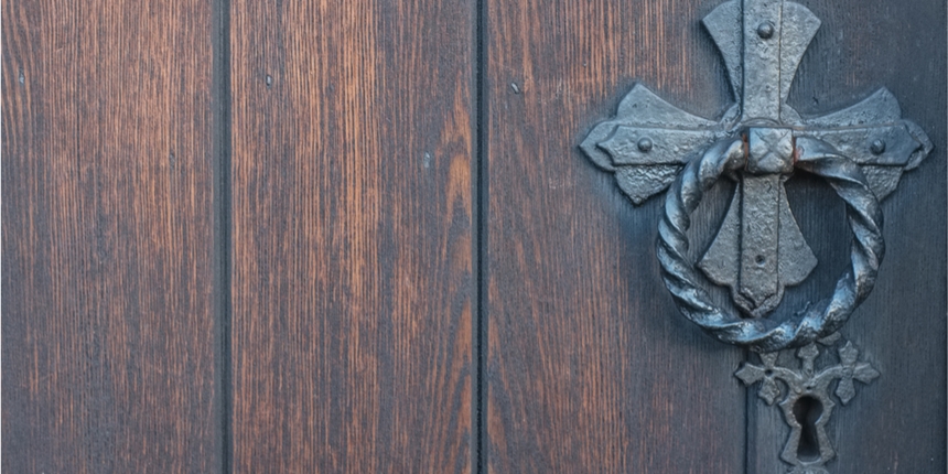 Close up of dark wooden door with wrought iron handle 